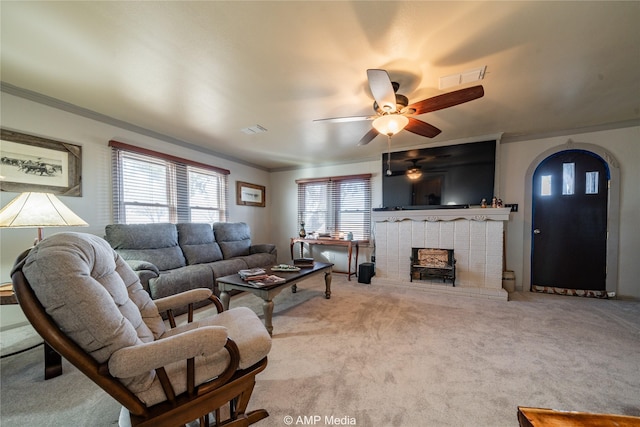 living room featuring ornamental molding, a brick fireplace, light carpet, and ceiling fan