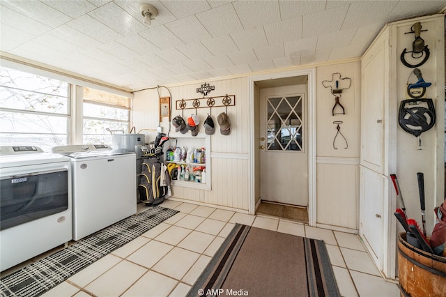 washroom featuring light tile patterned floors, wooden walls, and washing machine and clothes dryer