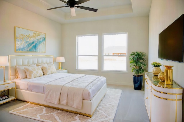 bedroom with ceiling fan, multiple windows, and a tray ceiling