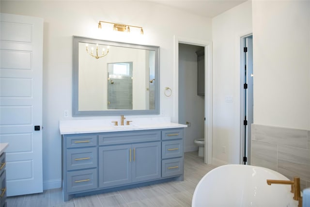 bathroom with a notable chandelier, a tub, vanity, and toilet