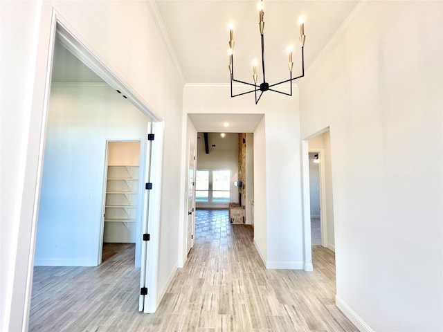 hall with a chandelier, crown molding, and light hardwood / wood-style flooring