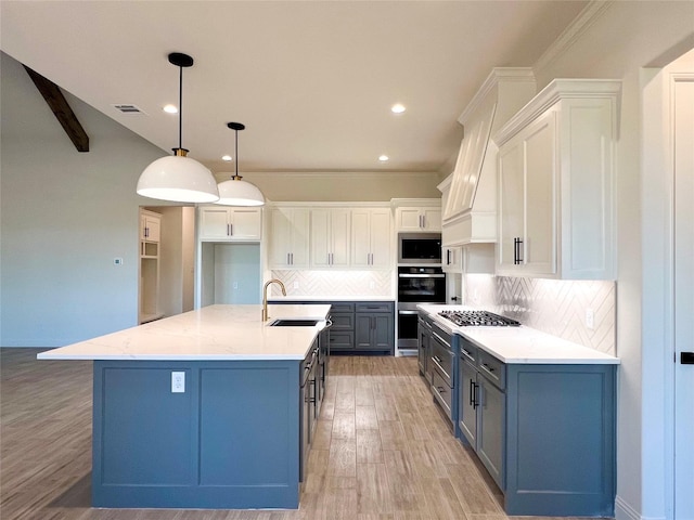 kitchen with white cabinets, tasteful backsplash, a center island with sink, and hanging light fixtures