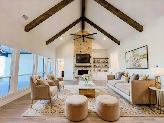 living room with light hardwood / wood-style floors, built in shelves, high vaulted ceiling, ceiling fan, and beamed ceiling