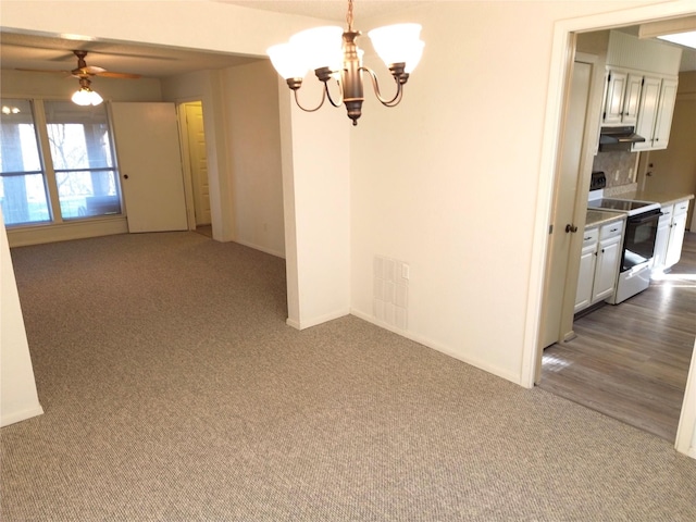 unfurnished dining area with dark carpet and ceiling fan with notable chandelier