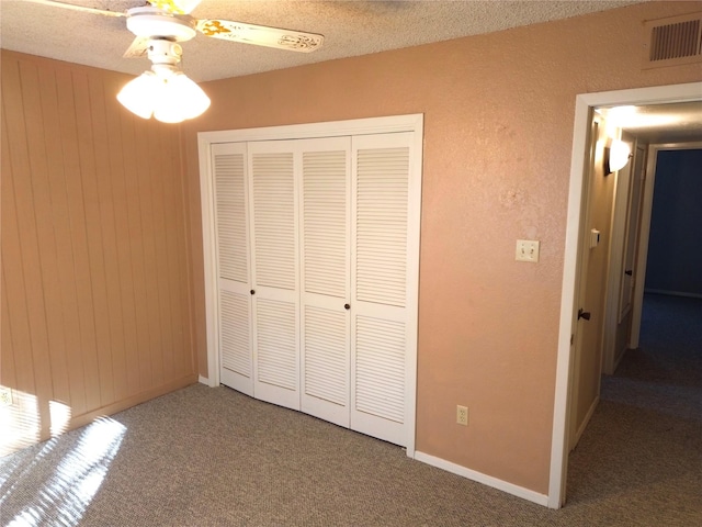 unfurnished bedroom featuring ceiling fan, a closet, carpet floors, and a textured ceiling