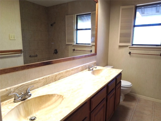 bathroom with tiled shower, vanity, and toilet