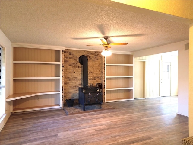 unfurnished living room featuring hardwood / wood-style floors, a textured ceiling, a wood stove, and ceiling fan