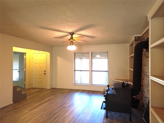 interior space featuring wood-type flooring, a textured ceiling, and ceiling fan