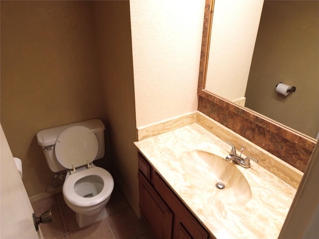 bathroom with toilet, vanity, and tile patterned floors