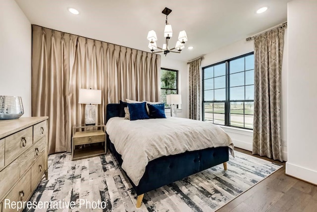 bedroom with multiple windows, light hardwood / wood-style flooring, and an inviting chandelier