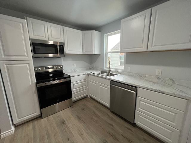 kitchen featuring white cabinetry, appliances with stainless steel finishes, sink, and hardwood / wood-style floors