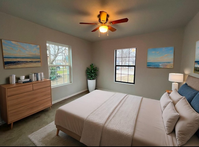 bedroom featuring multiple windows, dark carpet, and ceiling fan