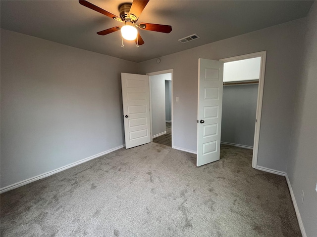 unfurnished bedroom with ceiling fan, a walk in closet, a closet, and carpet