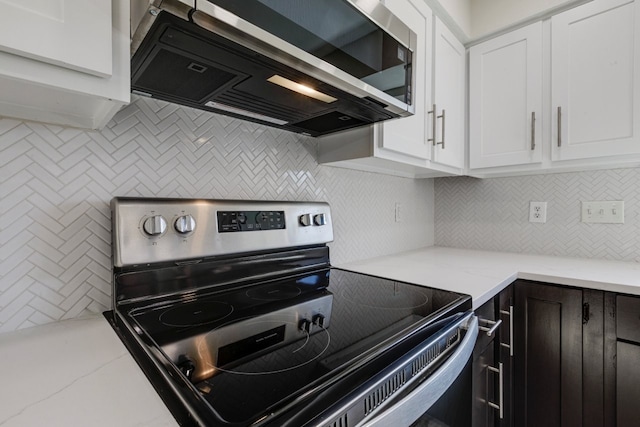 kitchen featuring light stone countertops, tasteful backsplash, white cabinetry, and stainless steel electric range