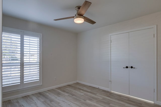 unfurnished bedroom with ceiling fan, light wood-type flooring, and a closet