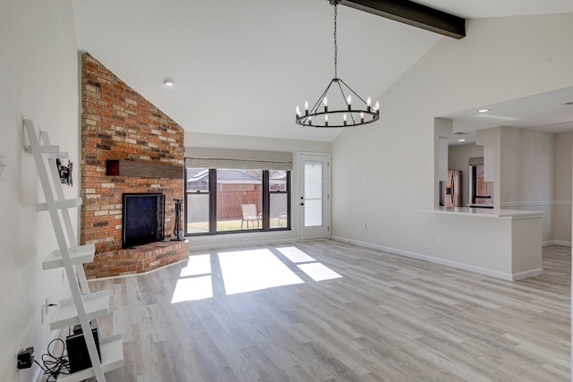 unfurnished living room featuring a chandelier, light hardwood / wood-style floors, a brick fireplace, and beamed ceiling