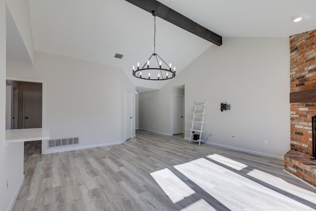 unfurnished living room with high vaulted ceiling, beamed ceiling, a chandelier, a fireplace, and light wood-type flooring