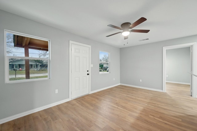 empty room featuring ceiling fan, a healthy amount of sunlight, and light hardwood / wood-style floors