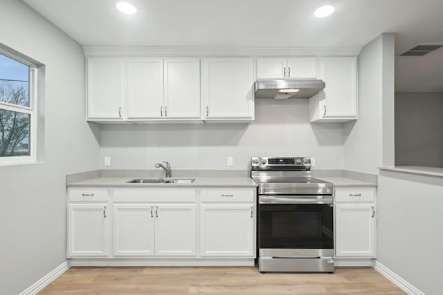 kitchen featuring stainless steel electric range, white cabinetry, and sink