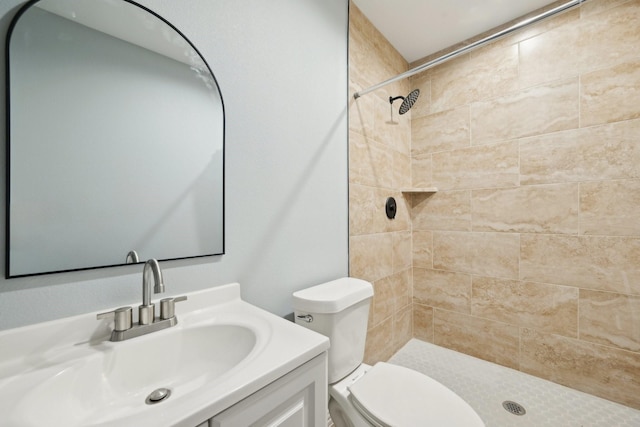 bathroom with tiled shower, vanity, and toilet