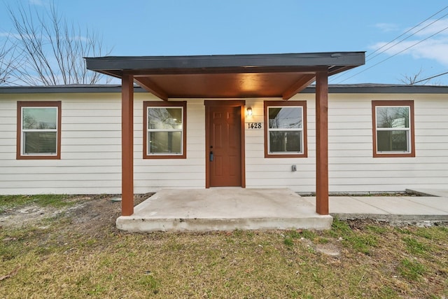 entrance to property with a lawn and a patio area