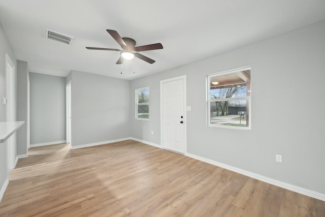 spare room with light wood-type flooring, a wealth of natural light, and ceiling fan