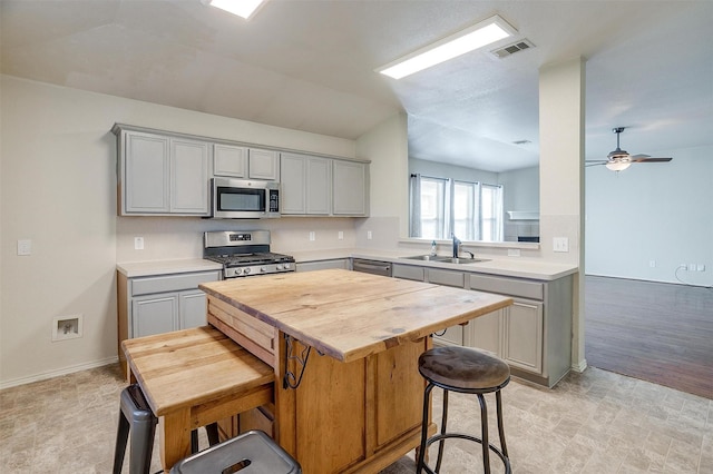 kitchen featuring gray cabinetry, ceiling fan, a kitchen breakfast bar, and stainless steel appliances