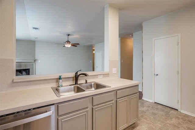 kitchen featuring a fireplace, ceiling fan, sink, and stainless steel dishwasher