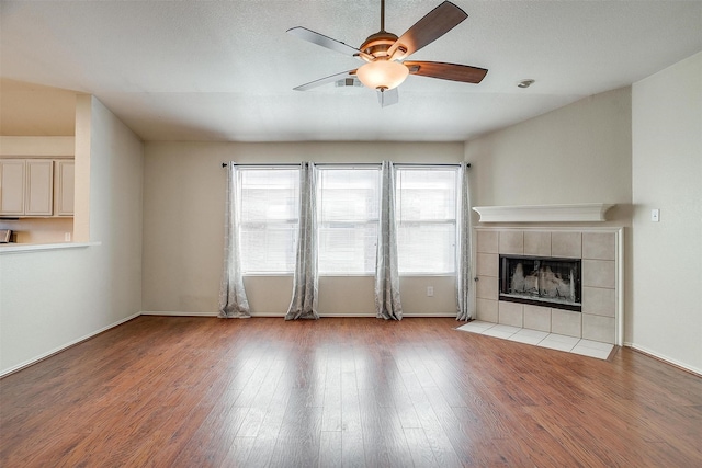 unfurnished living room featuring ceiling fan, a tile fireplace, and light hardwood / wood-style flooring