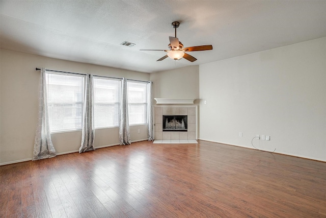 unfurnished living room with a tile fireplace, ceiling fan, and hardwood / wood-style floors