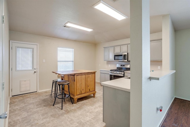 kitchen featuring kitchen peninsula, a breakfast bar, a center island, and stainless steel appliances