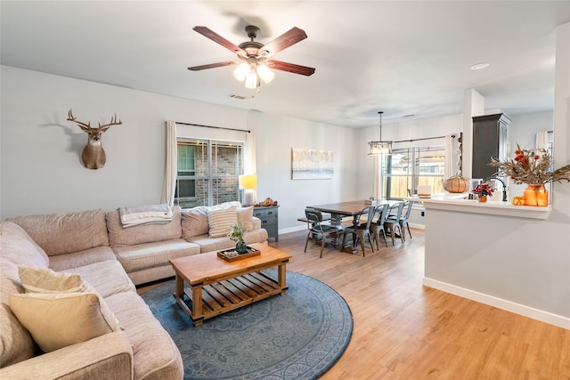 living room featuring wood-type flooring, plenty of natural light, and ceiling fan