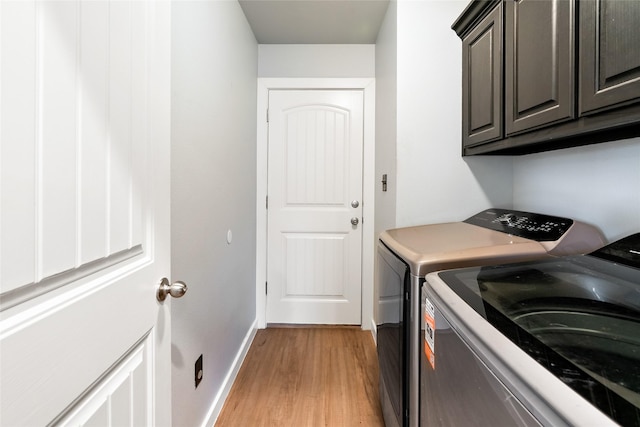 laundry room featuring cabinets, light wood-type flooring, and independent washer and dryer