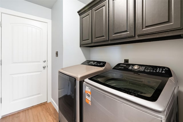 laundry room featuring washer and clothes dryer, light hardwood / wood-style floors, and cabinets