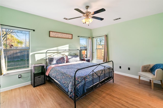 bedroom featuring multiple windows, ceiling fan, and light hardwood / wood-style flooring