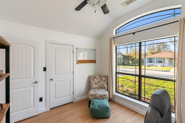 living area featuring ceiling fan, light hardwood / wood-style floors, and vaulted ceiling