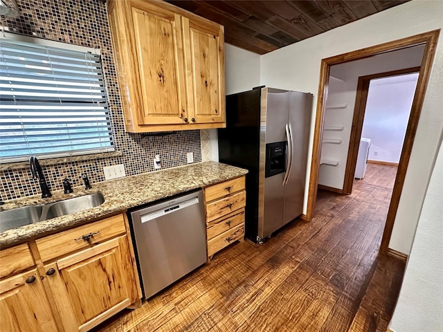 kitchen with sink, appliances with stainless steel finishes, dark hardwood / wood-style floors, light stone counters, and decorative backsplash