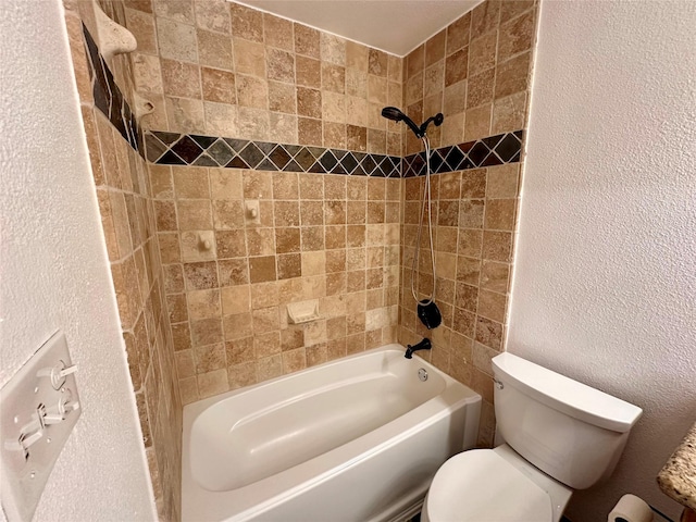 bathroom featuring toilet and tiled shower / bath