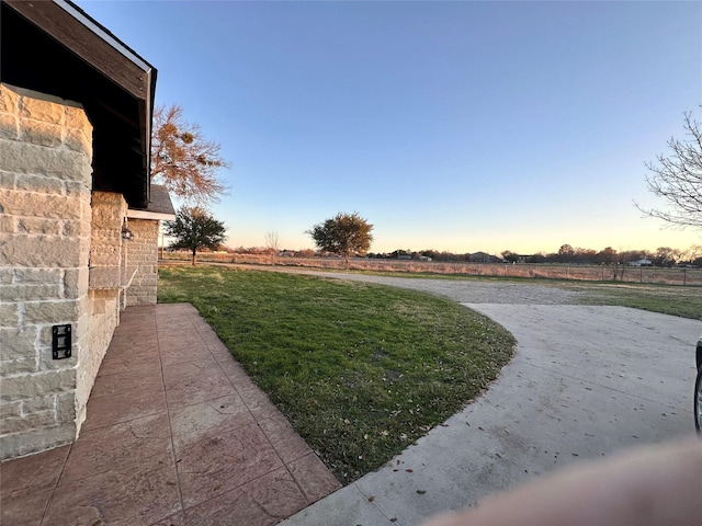 yard at dusk featuring a rural view