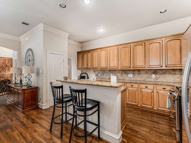 kitchen featuring decorative backsplash, a kitchen island with sink, dark hardwood / wood-style flooring, and light stone counters