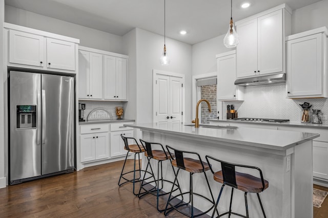 kitchen featuring a center island with sink, white cabinets, decorative light fixtures, and appliances with stainless steel finishes