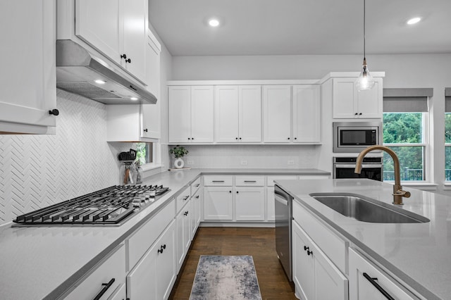 kitchen featuring pendant lighting, sink, appliances with stainless steel finishes, tasteful backsplash, and white cabinetry