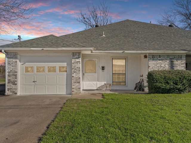 ranch-style home featuring a garage and a lawn