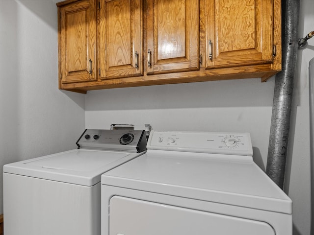 laundry room featuring washing machine and clothes dryer and cabinets