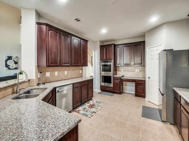 kitchen featuring tasteful backsplash, sink, light tile patterned floors, and appliances with stainless steel finishes