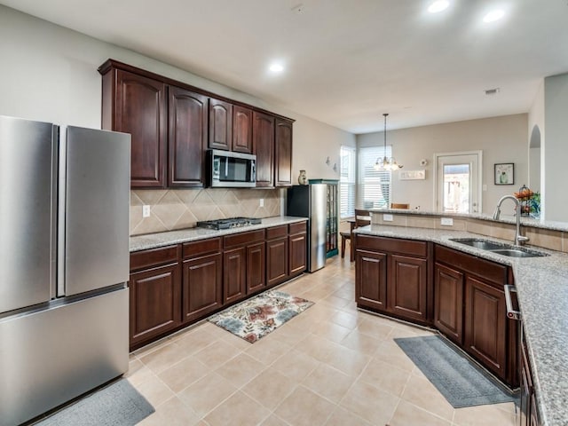 kitchen featuring sink, stainless steel appliances, backsplash, pendant lighting, and a chandelier