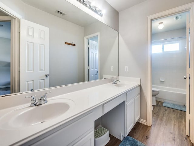 full bathroom featuring shower / bathing tub combination, hardwood / wood-style flooring, vanity, and toilet