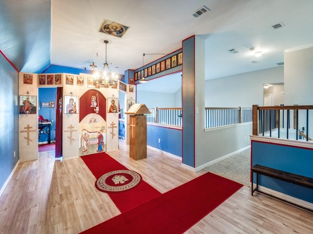 recreation room with a notable chandelier, vaulted ceiling, and hardwood / wood-style flooring