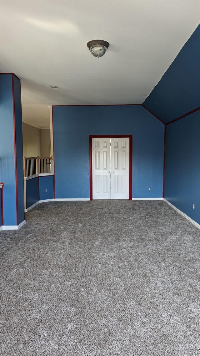 unfurnished bedroom featuring carpet, vaulted ceiling, and a closet