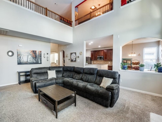 carpeted living room with a high ceiling and an inviting chandelier